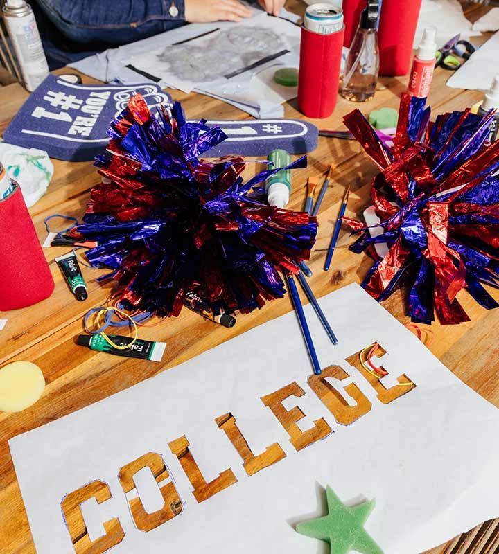 College stencil on a table with pom poms at a game day craft party