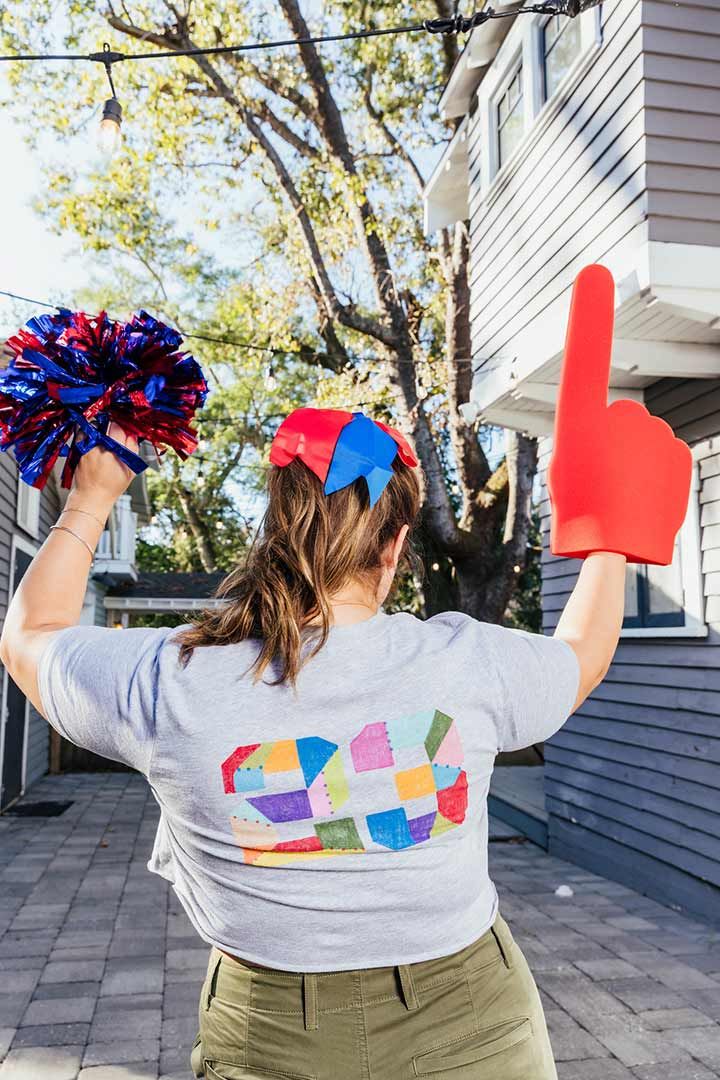 Woman cheering with pom poms and a custom tshirt at a game day party